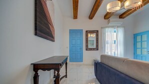 Un couloir avec une porte bleue, un miroir, une table en bois et un canapé bleu.