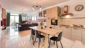 Una cocina moderna con una mesa de comedor de madera, sillas negras y un reloj en la pared.