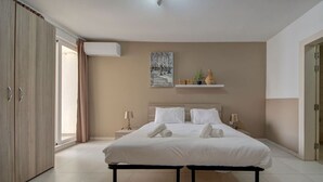 A modern bedroom with a large bed, bedside tables, a wardrobe, and a view of the outdoors.