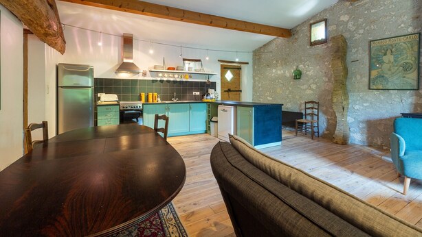 A rustic kitchen with wooden beams, a dining area with a wooden table and chairs, and a stone wall with a framed picture. - Holiday Home 'Chant D'Etoiles' with Private Pool (Roynac)