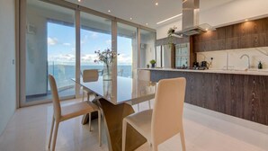 A modern kitchen with a glass partition, a dining area with a view, and a wooden accent wall.