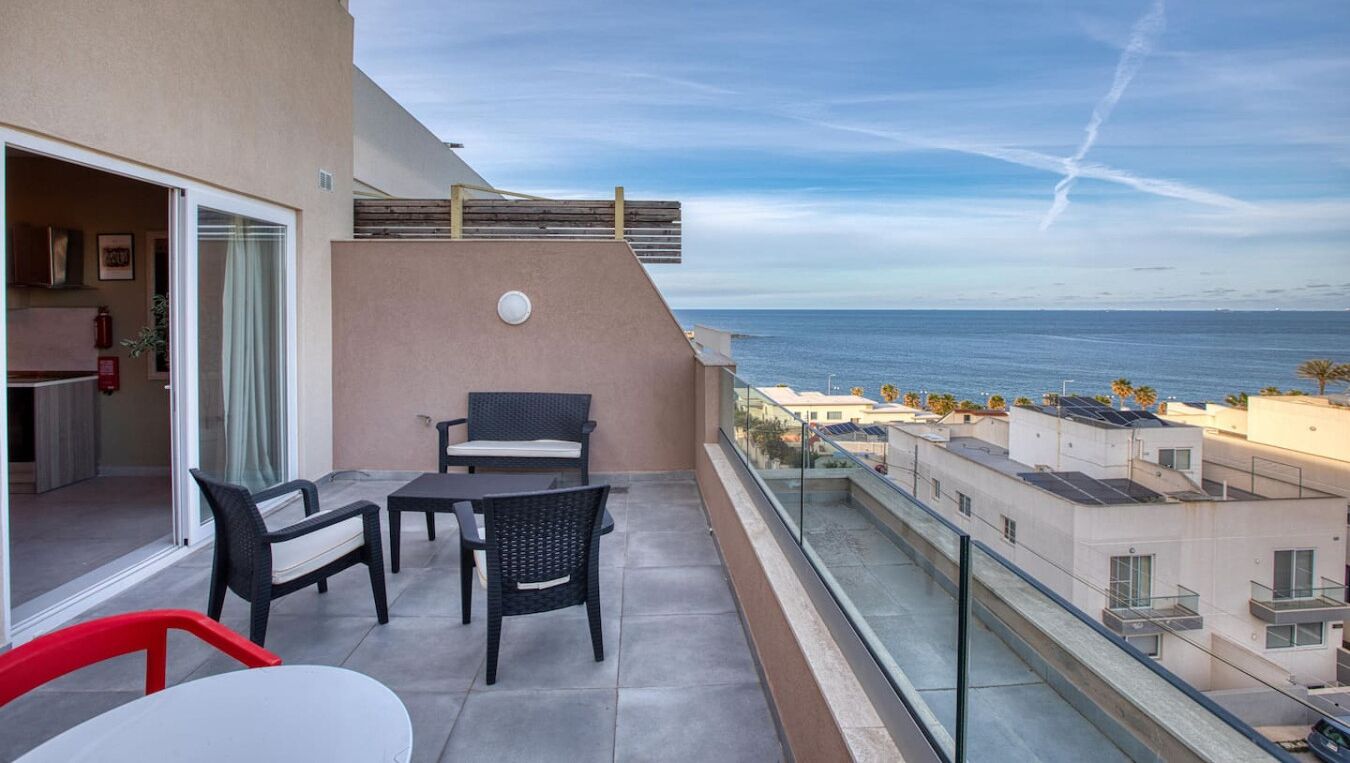 Un balcon avec vue sur l’océan, une table et deux chaises.