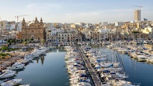 A marina filled with boats, a historic church, and a modern building under construction.