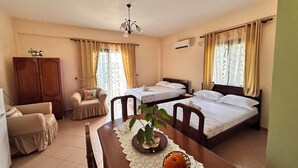 A hotel room with two single beds, a wooden wardrobe, a dining table with a placemat, and a potted plant. - Apartments Meleqi (Ksamil)