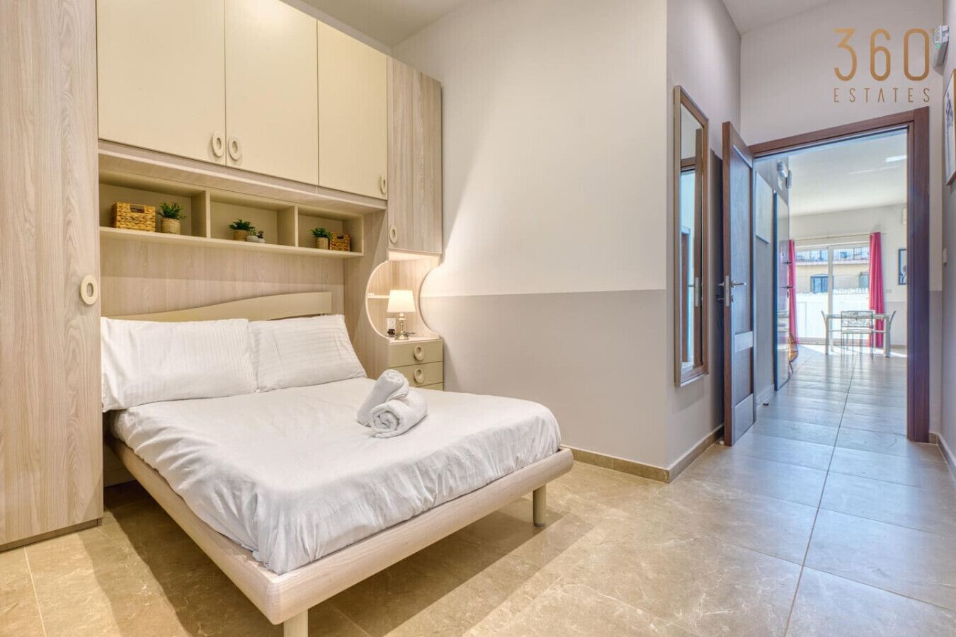 Une chambre moderne avec un lit, une table de chevet, une lampe et des rangements intégrés.