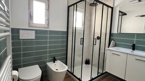 Ein modernes Badezimmer mit Duschkabine, Bidet und Waschbecken mit Spiegel.