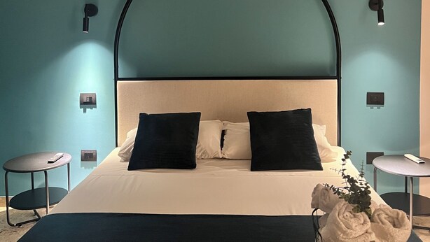 Ein modernes Hotelzimmer mit einem großen Bett, zwei Nachttischen und einem einzigartigen, gewölbten Deckenbau.