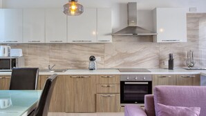 A modern kitchen with white cabinets, a built-in oven, and a coffee maker on the counter. - Sunlit Sliema 2BR Penthouse, Steps to Seafront! (Sliema)