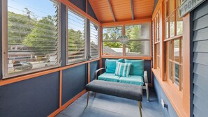 A cozy porch with a bench and a cushioned seating area, large windows, and a sign reading "Better Porch."