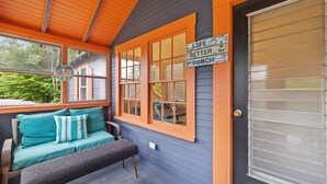 A porch with a bench and a couch, a door, and a sign that reads "Life is better on the porch."