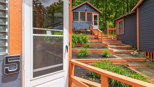 A residential property with a wooden deck, a small garden, and a blue house with a chimney.