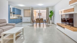A modern living room with a sofa, coffee table, and dining area with chairs and a table.