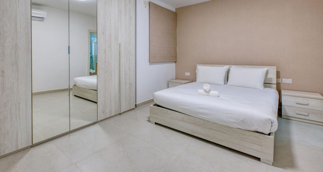 Una camera da letto con un letto, comodini, uno specchio e un armadio.