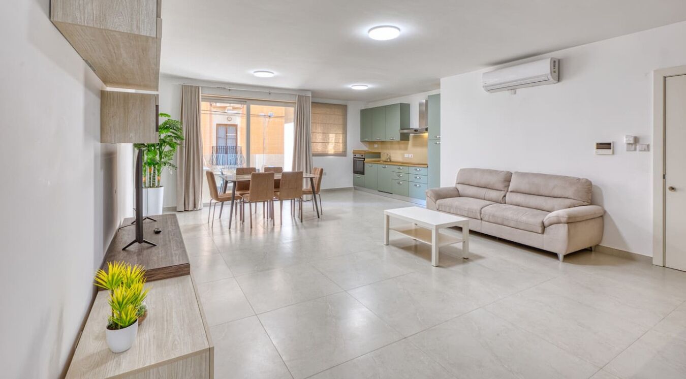 A modern living room with a sofa, coffee table, and dining area.