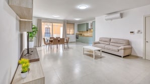 Ein modernes Wohnzimmer mit Sofa, Couchtisch und Essbereich.