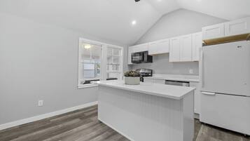 Una cocina moderna con armarios blancos, una isla central, un microondas y un refrigerador.