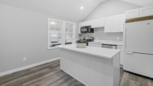 Una cocina moderna con armarios blancos, una isla central y un microondas integrado.