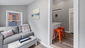 Ein modernes Wohnzimmer mit einem grauen Sofa, einem kleinen Hocker und einer hellen Leuchte.