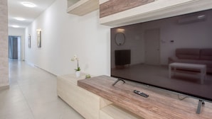 A modern living room with a large flat-screen TV, wooden console, and a minimalist design.