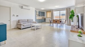 A modern apartment with a living room, dining area, kitchenette, and a balcony. - Mellieha 3BR home with Rooftop Pool Access w/AC`s (Mellieħa)