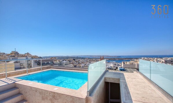 A rooftop pool with a clear view of the cityscape and coastline.