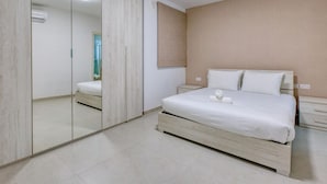 A bedroom with a bed, bedside tables, a mirror, and a wardrobe.