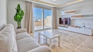 A modern living room with a sofa, a coffee table, and a TV on a white entertainment unit.