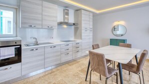 Eine moderne Küche mit Backofen, einer Spüle aus Edelstahl und einem Essbereich mit weißem Tisch und gepolsterten Stühlen.