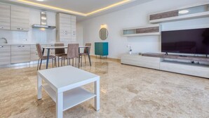 Ein modernes Wohnzimmer mit Essbereich, einem Flachbildfernseher und integrierten Schränken.