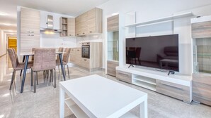 A modern living room with a flat-screen TV, a dining area with chairs, and built-in cabinetry.