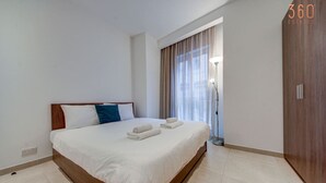 Une chambre d’hôtel avec un grand lit, une table de chevet, une lampe et une fenêtre avec des rideaux.