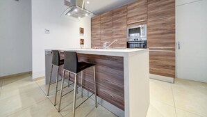 Une cuisine moderne dotée d’un îlot central, d’appareils électroménagers en acier inoxydable et d’un design minimaliste.