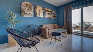 Una sala de estar moderna con un sofá, dos sillones negros, una mesa de centro de vidrio y un ventanal con vistas.