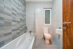 Une salle de bain moderne équipée d’une baignoire, de toilettes et d’un espace douche.