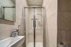 A modern bathroom with a glass-enclosed shower, a white sink, and a mirror above the sink. - Lovely 4BR home with private Terrace in Marsascala (Marsaskala)