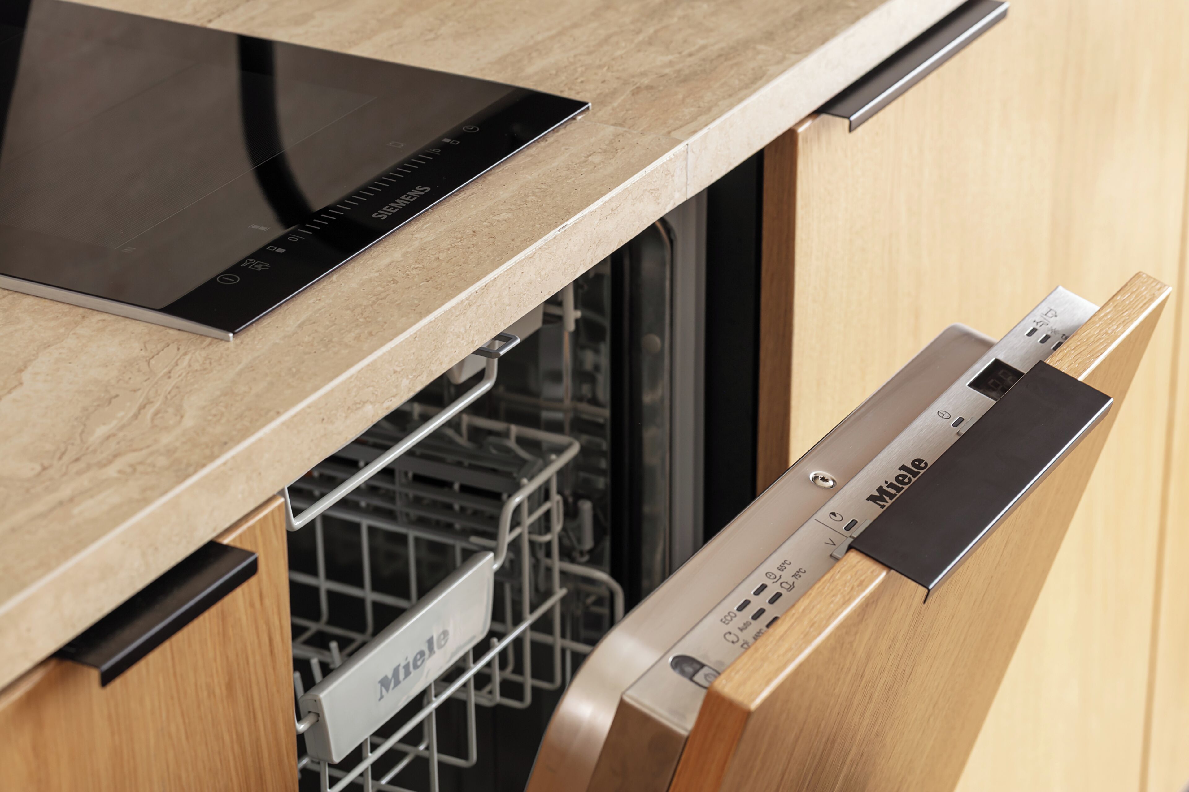 A kitchen with a dishwasher, a control panel, and a wooden cabinet.