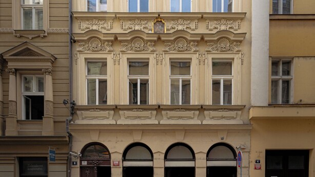 Un edificio de varios pisos con detalles arquitectónicos clásicos, incluyendo molduras ornamentales y una fachada simétrica.