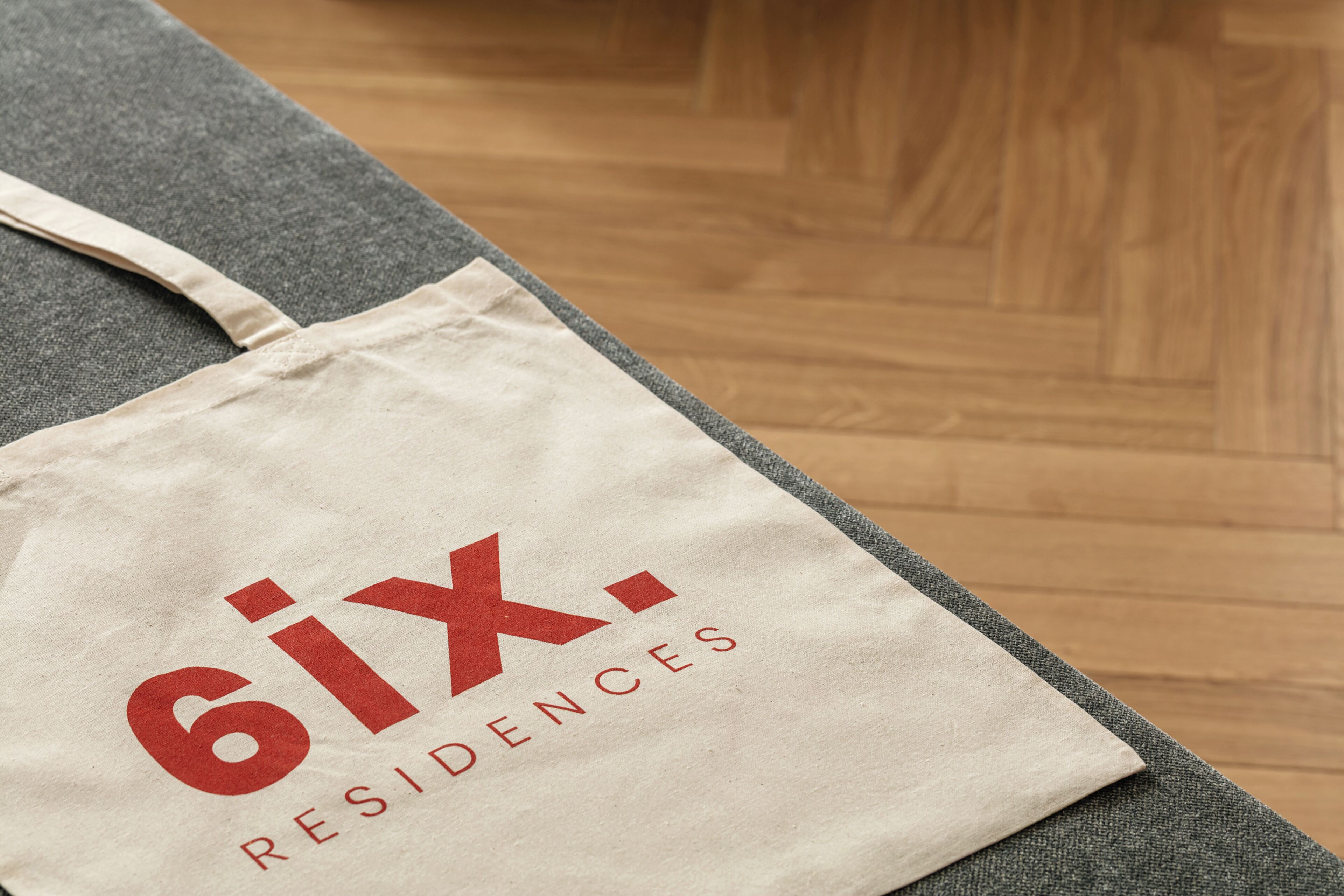Una bolsa de tela color beige con la inscripción '6ix Residences' en rojo.