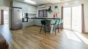 A modern kitchen with a central island, bar stools, and a view to the outside.