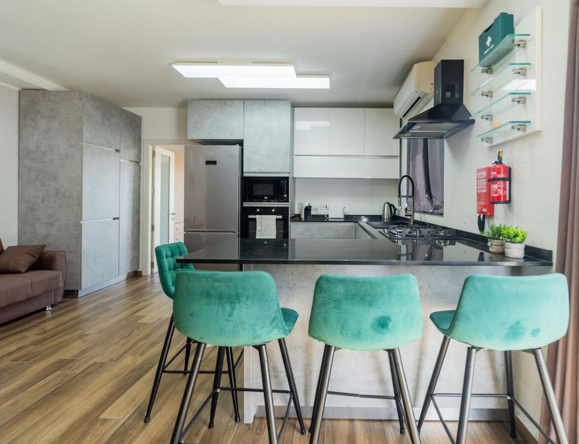 Een moderne keuken met een centraal eiland, barkrukken en een zithoek met een bank.