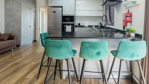 A modern kitchen with a central island, bar stools, and a dining area with a sofa.