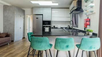 Een moderne keuken met een centraal eiland, barkrukken en een zithoek met een bank.