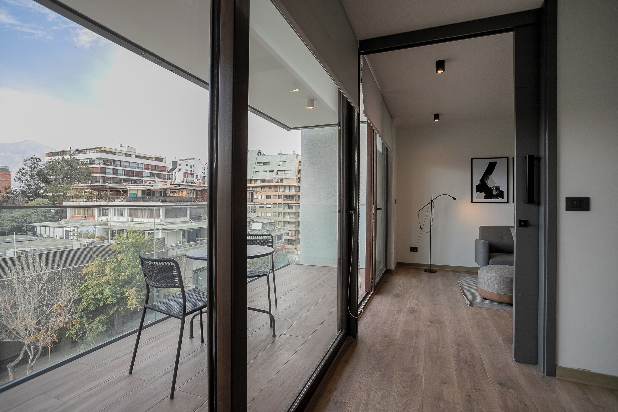 A modern interior with a balcony, a dining area, and a view of the cityscape.