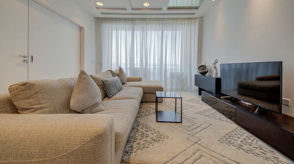Un salon moderne comprenant un canapé, un téléviseur à écran plat et une table basse.