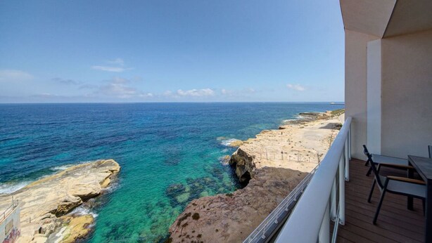Un balcón con vista al océano y a la costa rocosa.