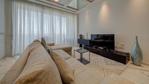 Una sala de estar moderna con un sofá, un televisor de pantalla plana, una mesa consola y un jarrón decorativo.