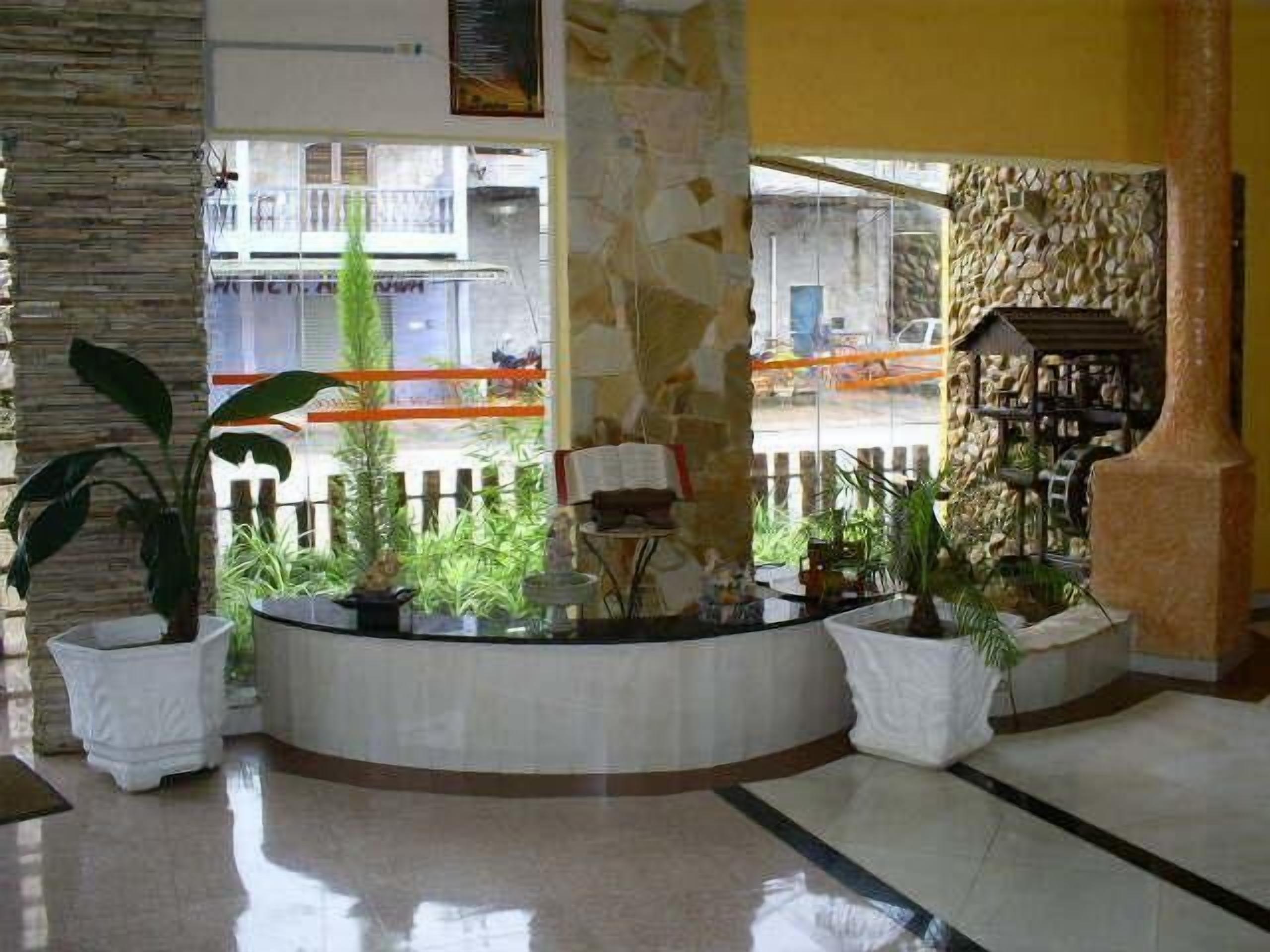 Um hall com um pilar de pedra, balcão de recepção e plantas em vasos.