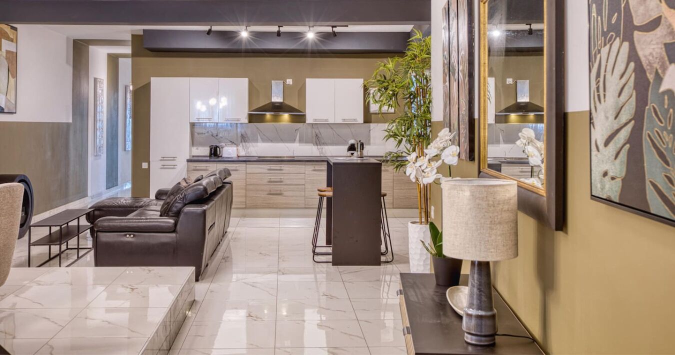 A modern living room with a leather sofa, a coffee table, and a large mirror.
