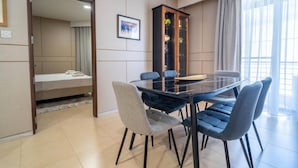 Ein modernes Hotelzimmer mit einem Glastisch, vier Stühlen, einer Couch, einem Schrank und einem Bett.