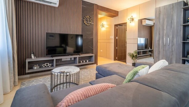 Ein modernes Wohnzimmer mit Fernseher, einer Couch, einem Couchtisch und einer Wanduhr.